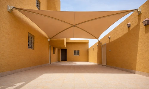Modern tensile car parking shade design at a residential building, installed by leading car parking shade companies in Saudi Arabia.