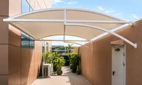 Tensile entrance canopy installed outside building pathway.
