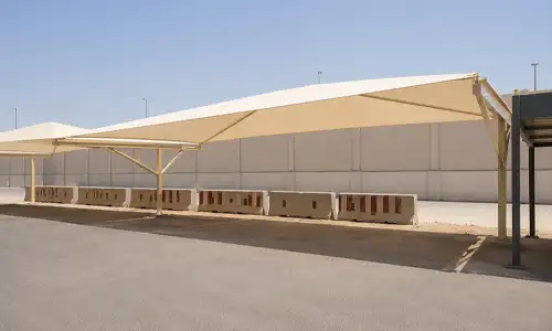 Long-span industrial parking shelter with extended roof coverage.