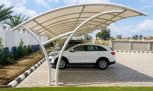 Modern curved car shade placed in an outdoor parking area.